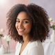 Smiling young woman with voluminous, styled curls, looking confidently at the camera.